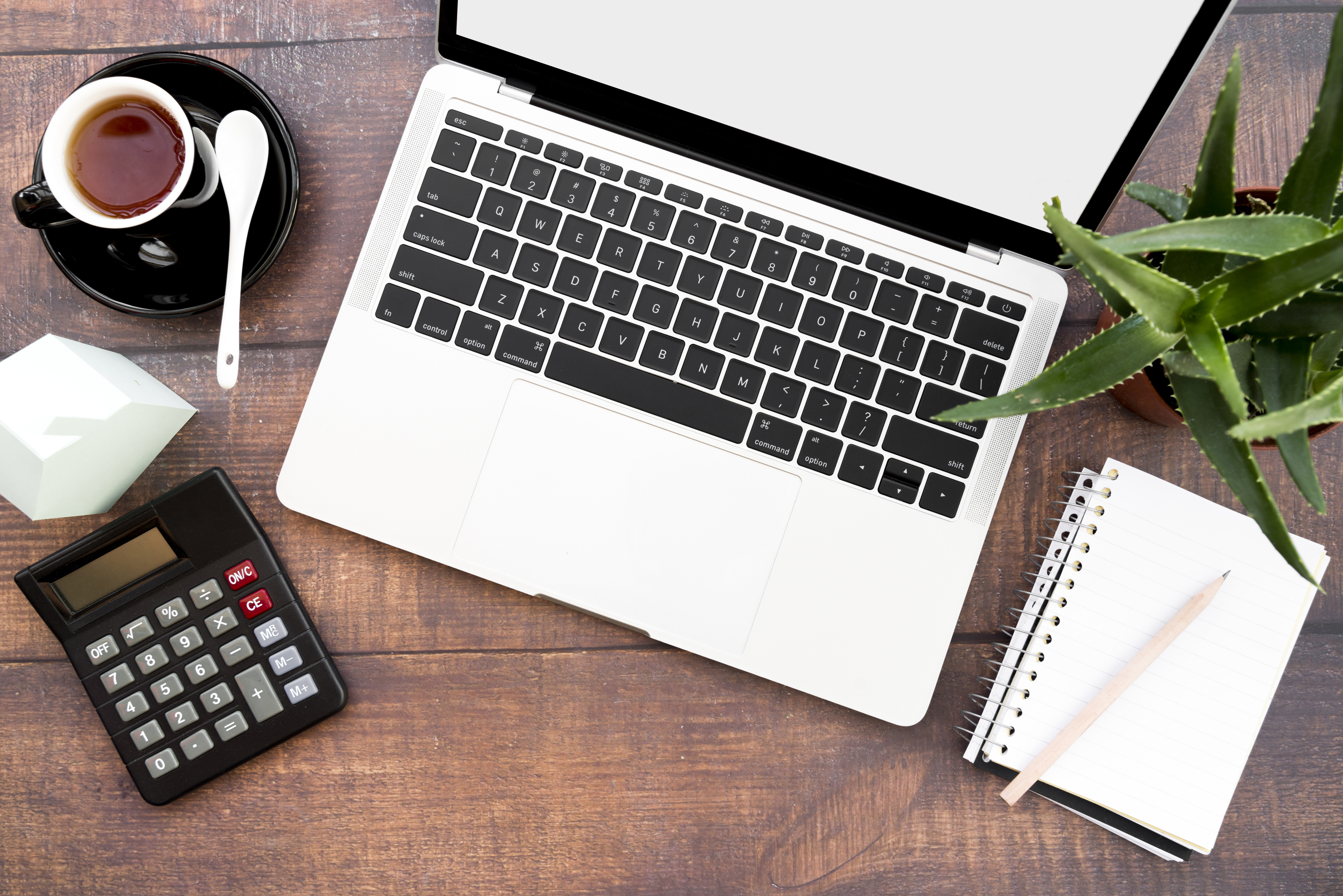 open-laptop-with-coffee-cup-spiral-notebook-calculator-paper-house-model-aloe-vera-plants-wooden-table-1