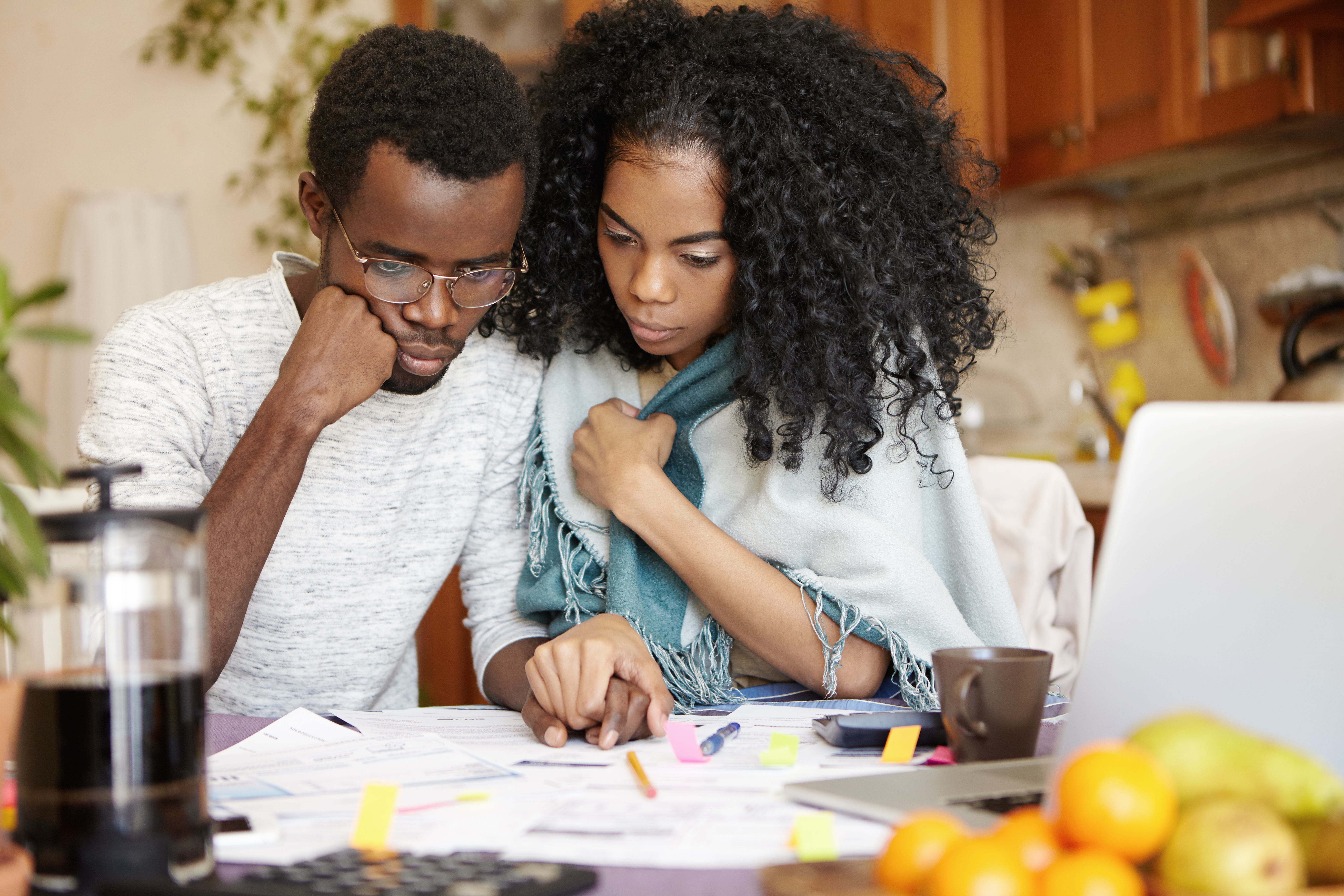 young-dark-skinned-couple-managing-finances-sitting-kitchen-table-with-stressed-looks